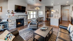 A spacious living room with a fireplace, leather sofas, a dining area, and a kitchen.