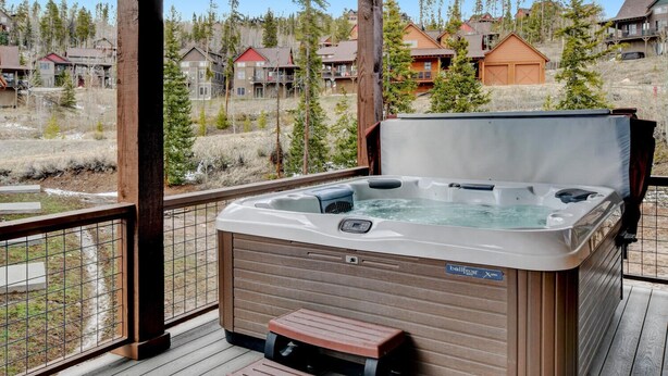 A hot tub on a wooden deck with a view of surrounding cabins.