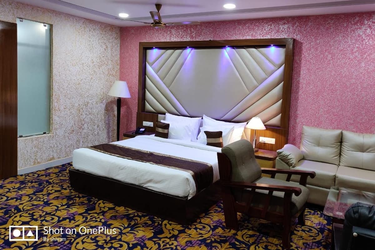 A hotel room with a large bed, a sofa, a chair, and a desk.