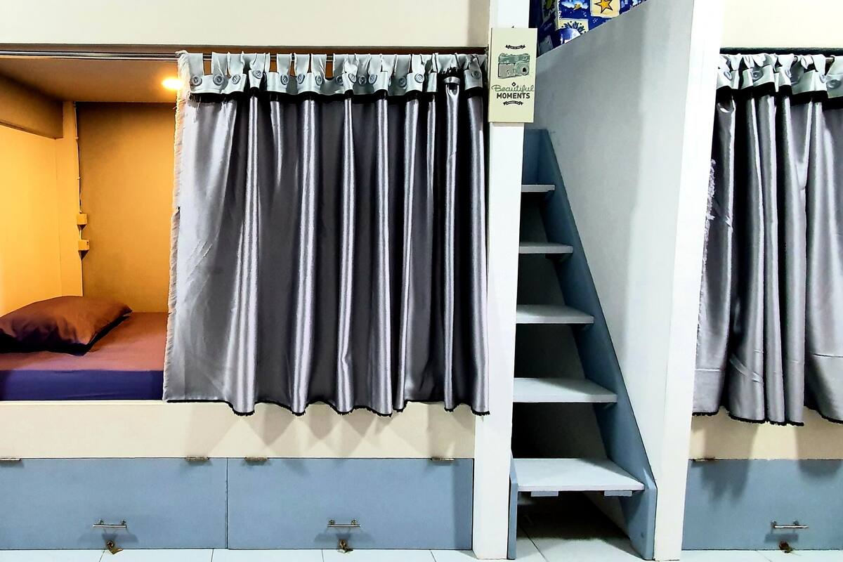 Um quarto de dormitório com uma cama, uma escrivaninha e uma escada.