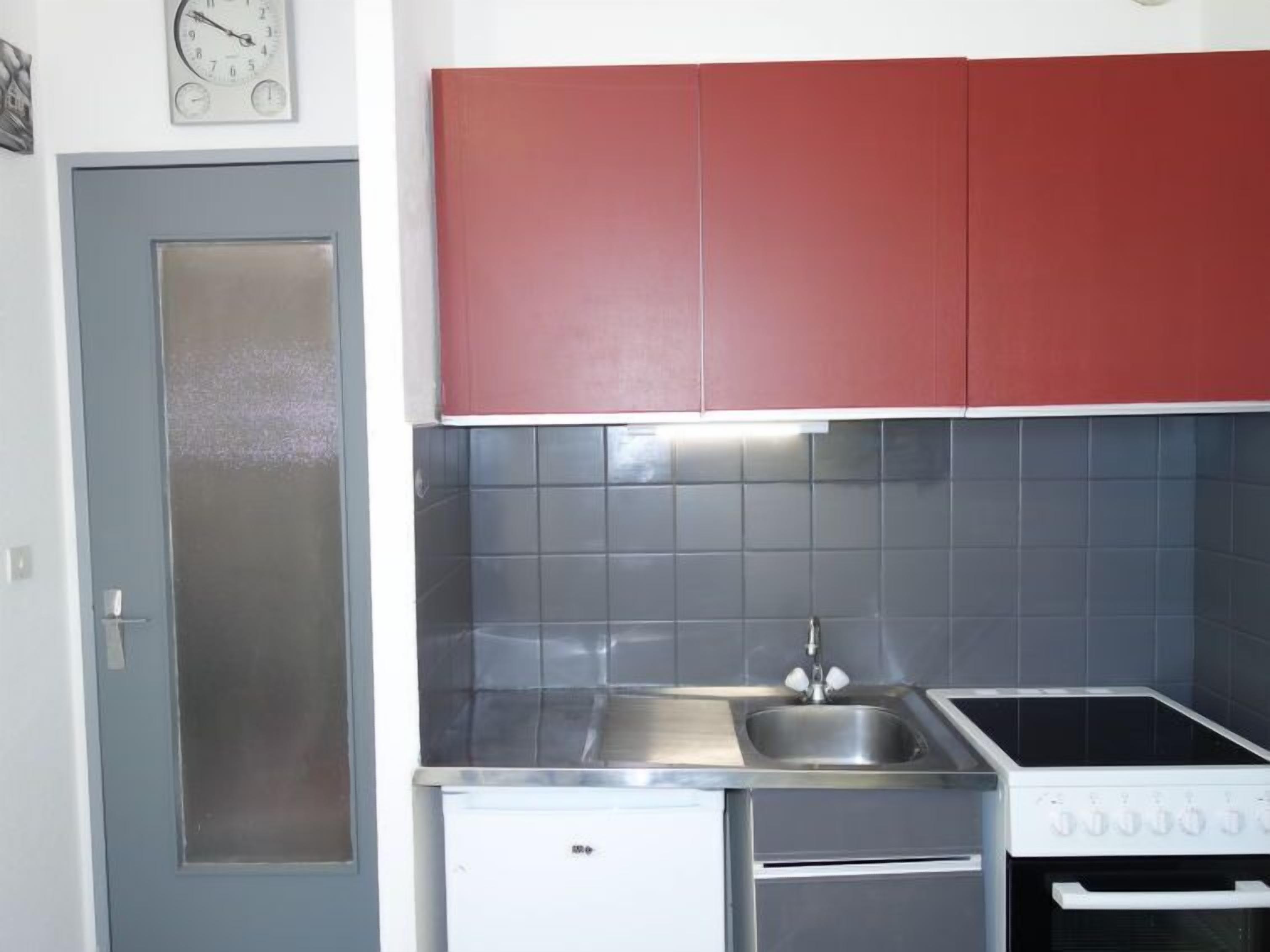 Een kleine keuken met een spoelbak, fornuis en een compacte koelkast.