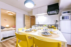 A compact kitchen with white cabinets, a black range hood, and a white refrigerator. - Heights Showa 606 (Sapporo)