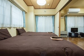 A bedroom with a large bed, a TV, and an air conditioning unit. - Heights Showa 606 (Sapporo)