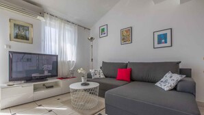 Un soggiorno moderno con un divano grigio, una televisione a schermo piatto e un tavolino da caffè bianco.