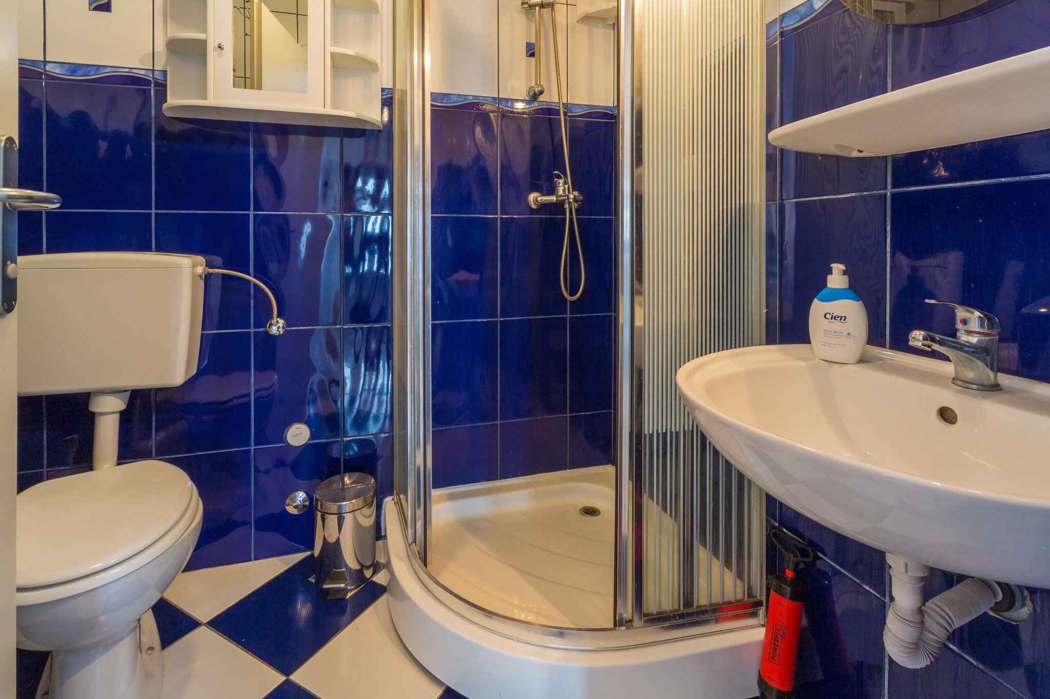 A bathroom with a toilet, a shower with a glass door, and a sink with a mirror above it.