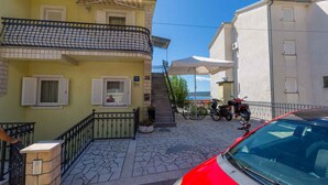 Una strada residenziale con un edificio giallo, un edificio bianco e un'auto rossa parcheggiata davanti.