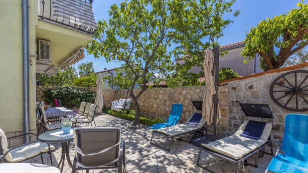 An outdoor patio with stone flooring, lounge chairs, and a table with a potted plant. - Holiday apartment mit Klimaanlage und Balkon (Selce)