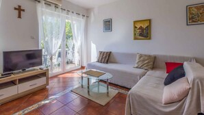 A living room with a TV, sofa, and artwork on the walls. - Holiday apartment mit Klimaanlage und Balkon (Selce)