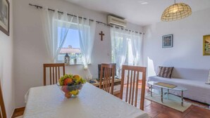 A dining area with a table set for two, a bowl of fruit, and a sofa in the background. - Holiday apartment mit Klimaanlage und Balkon (Selce)