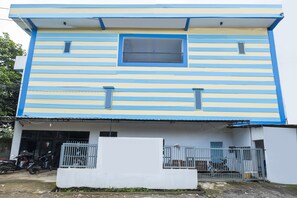 A two-story building with a blue and white striped facade, a small window, and a gated entrance.