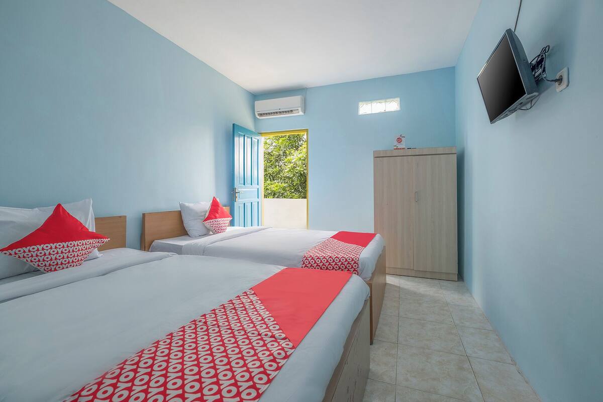 Une chambre d’hôtel avec deux lits, une télévision, la climatisation, une armoire et une fenêtre donnant sur un beau paysage.