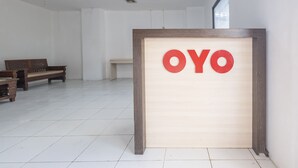 A reception area with a wooden sign reading "OYO" and a bench in the background. - Hotel O RF Homestay (Makassar)