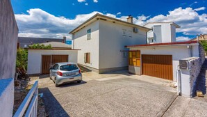 Una propiedad residencial con garaje para dos coches, una construcción adicional pequeña y un camino de entrada pavimentado.