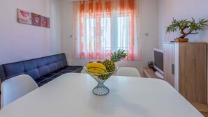 Un comedor con una mesa blanca, un banco acolchado negro y un frutero con plátanos y una piña.