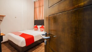 A hotel room with a bed, a wooden wardrobe, and a window with curtains. - Hotel O Sutomo Inn (Medan)