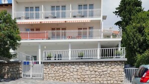 A multi-story building with balconies, a stone wall, and a paved entrance area. - Holiday apartment mit Meerblick und Klimaanlage (Novi Vinodolski)