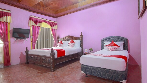 A room with two beds, a TV mounted on the wall, and a wooden ceiling. - OYO 2838 Hotel Ayu (Bengkulu)