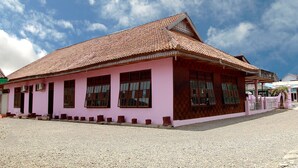 A pink building with a tiled roof and multiple windows. - OYO 2838 Hotel Ayu (Bengkulu)