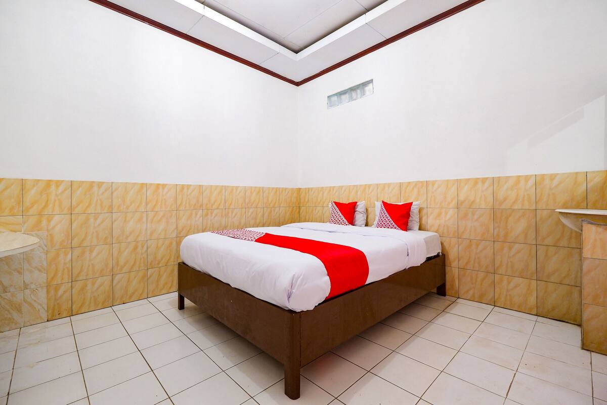 A neatly arranged hotel room with a bed, a bedside table, and a small sink.