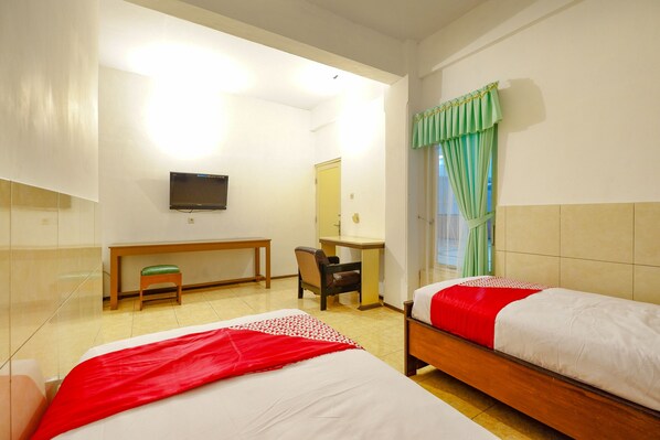A hotel room with two beds, a desk, a chair, a television, and a window with curtains. - OYO 2855 Sartika Hotel Pati (Pati)
