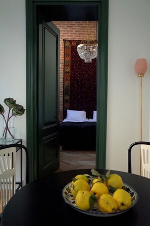 A dining table with a plate of lemons, a vase with flowers, and a chandelier in the background.