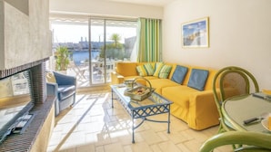 A bright living room with a yellow sofa, a glass table, and a view of the sea. - Vacation home Hélios by Interhome (Port Camargue)