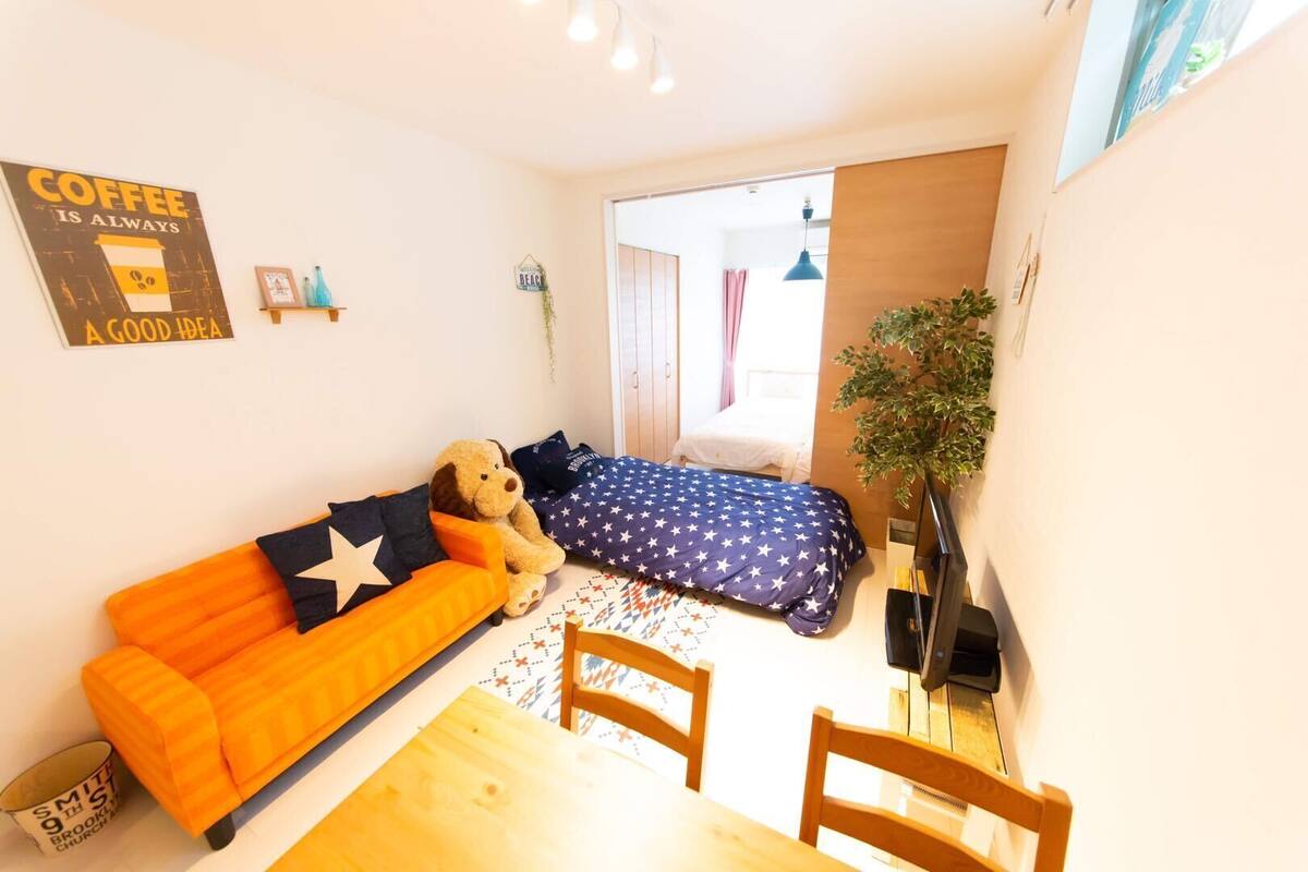 A cozy room with a sofa, a bed, a dining table, and a TV.