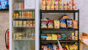 A vending machine with a variety of snacks and drinks, a shelf stocked with packaged goods, and a fire extinguisher mounted on the wall. - Signature by The Concept (Langkawi)