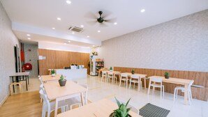 A modern dining area with white tables and chairs, a ceiling fan, and a wooden counter in the background. - Signature by The Concept (Langkawi)