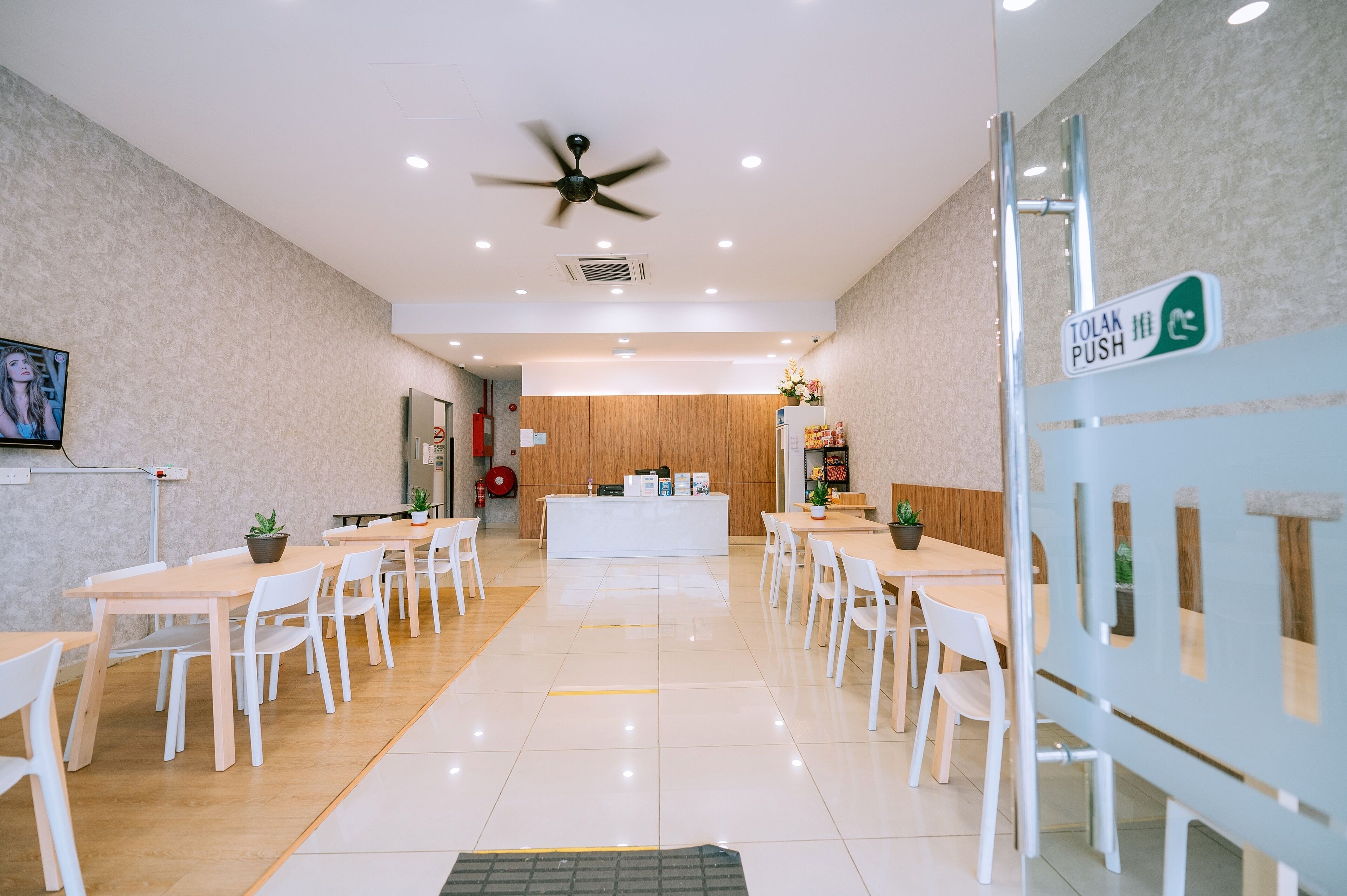 Un área de recepción moderna con mostrador, sillas blancas y un ventilador de techo.