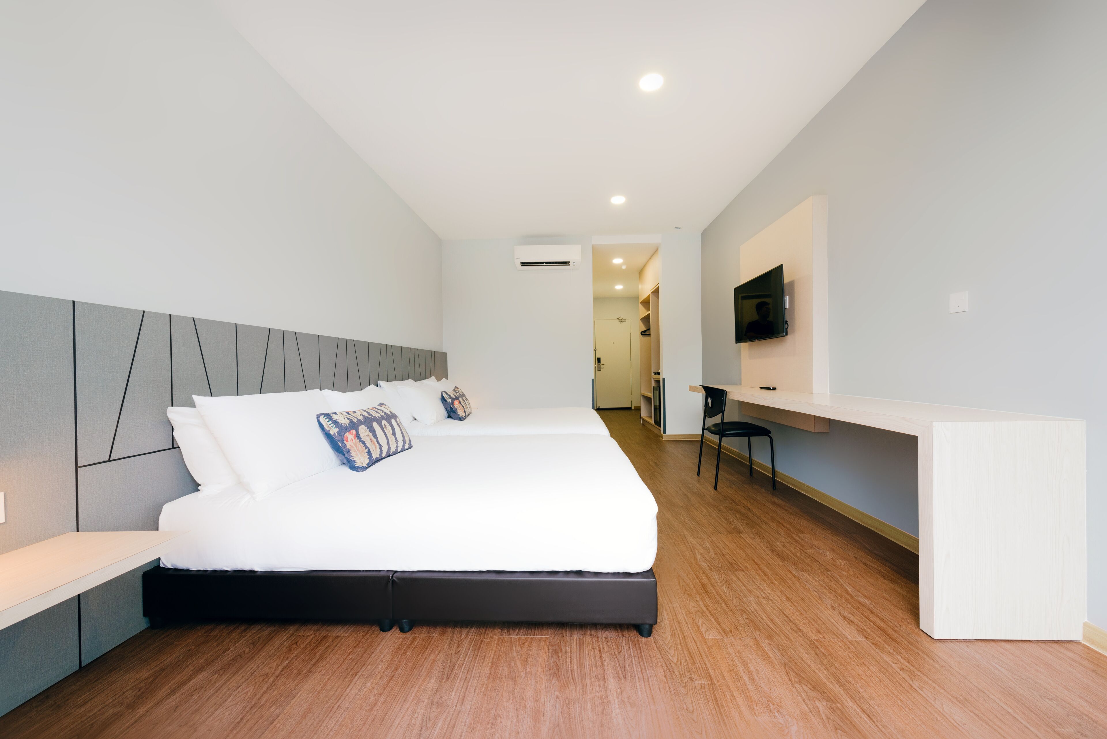 A modern hotel room with a large bed, a desk, and a TV.