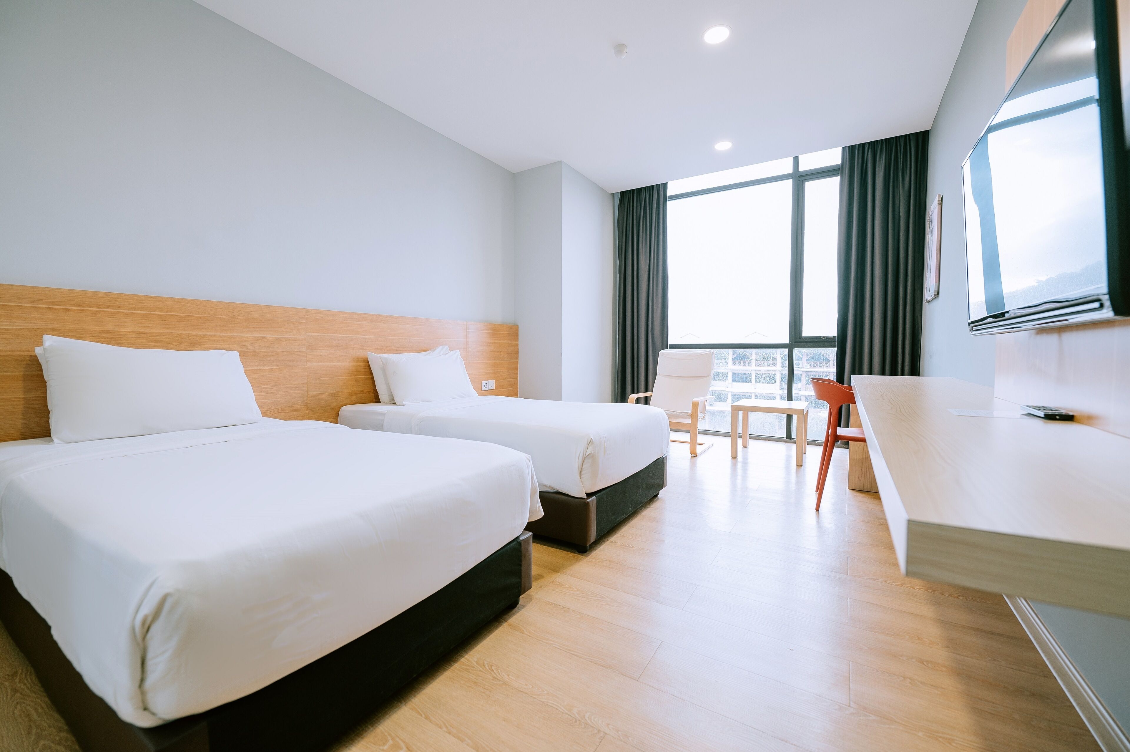 A hotel room with two beds, a desk, and a chair.