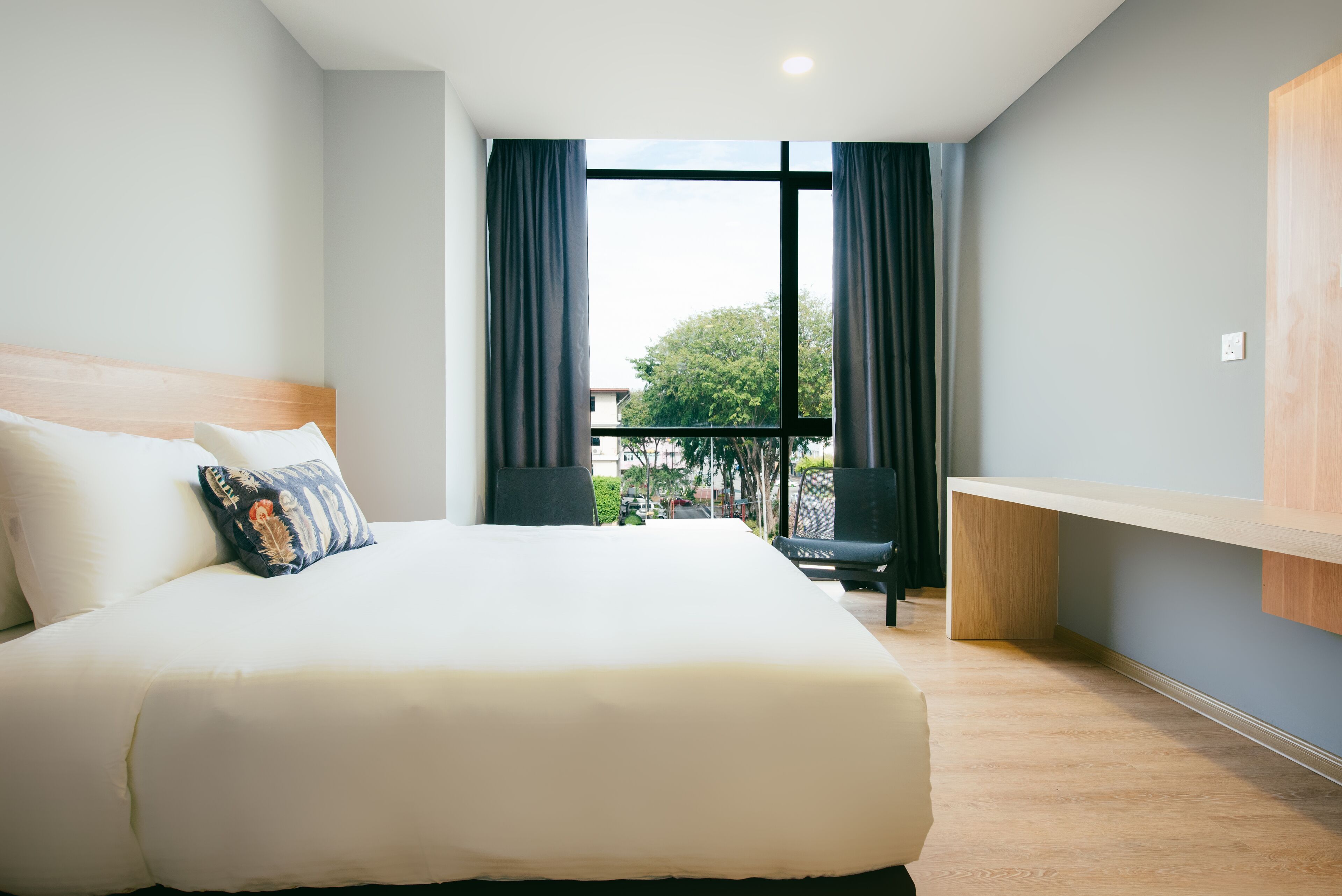 Habitació d'hotel amb un llit gran, una taula de treball, una cadira i un balcó amb vistes.