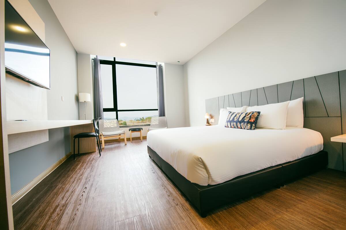 Ein modernes Hotelzimmer mit einem großen Bett, einem Schreibtisch und einem Sessel.