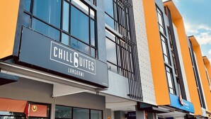 A modern building with a 'Chill Suites' sign, large windows, and a clear sky. - Signature by The Concept (Langkawi)