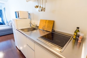 A modern kitchen with a built-in stove, a microwave, and a wooden cutting board.