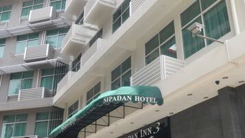 A multi-story building with balconies, a sign for 'Sipadan Hotel', and a 'Gipadan Inn 3' sign.