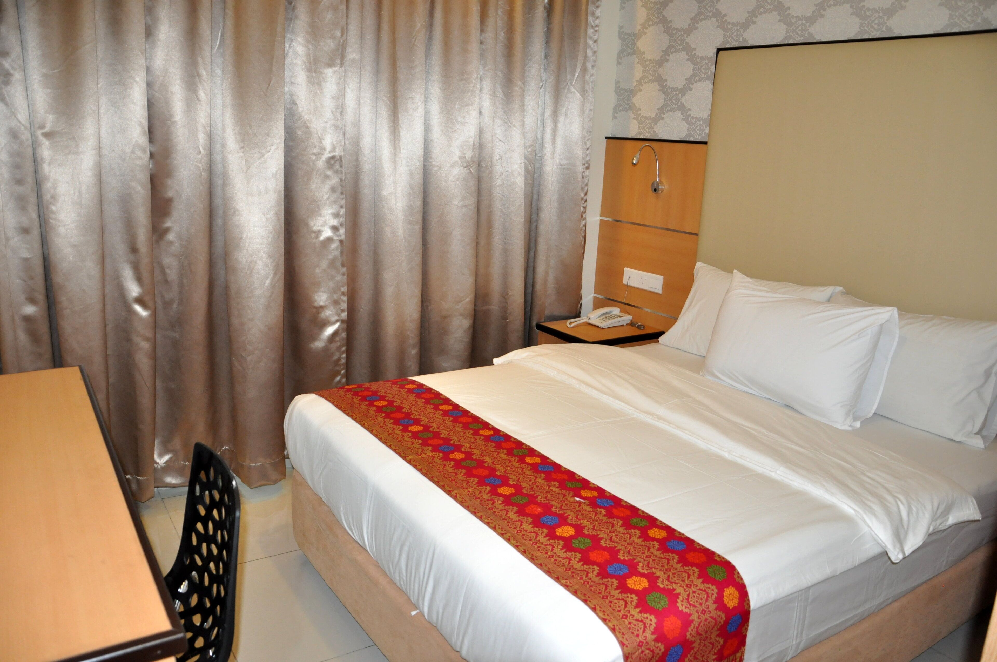 Une chambre d’hôtel équipée d’un lit, d’un bureau, d’une chaise et d’un téléphone.