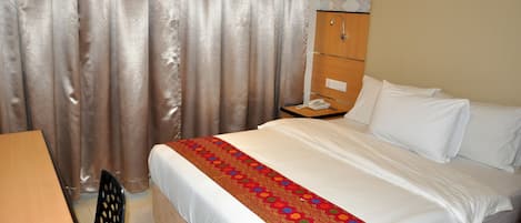 A hotel room with a bed, a desk, a chair, and a telephone.
