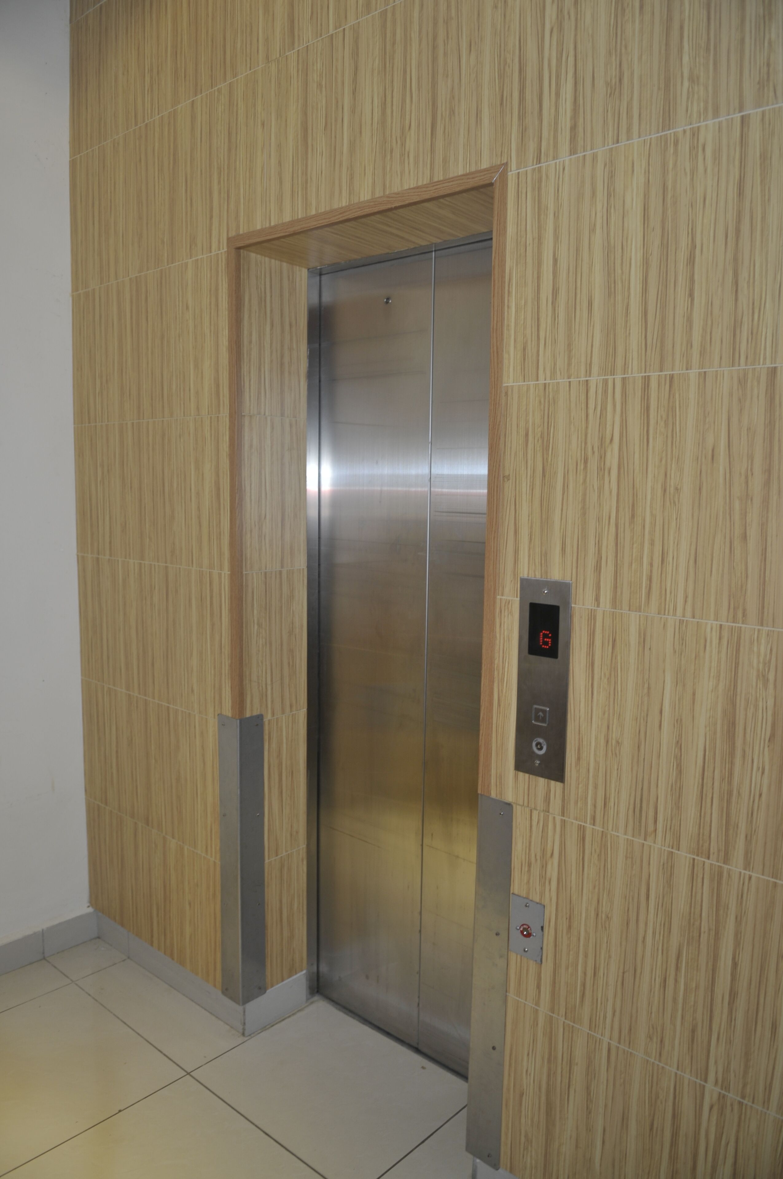 Un ascensor con paneles de madera y un panel de control con pantalla digital.