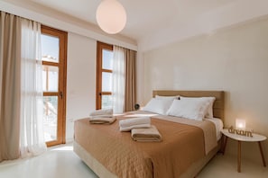 Une chambre avec un grand lit, une table de chevet avec une lampe et une vue par la fenêtre.