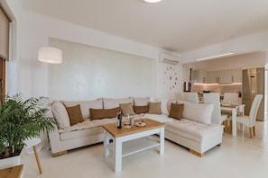 Un salon moderne avec un canapé d’angle, une table basse en bois et un coin repas comprenant une table et des chaises.