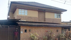 Une maison à deux étages, avec un toit en tuiles, une façade en briques et une entrée fermée par un portail.