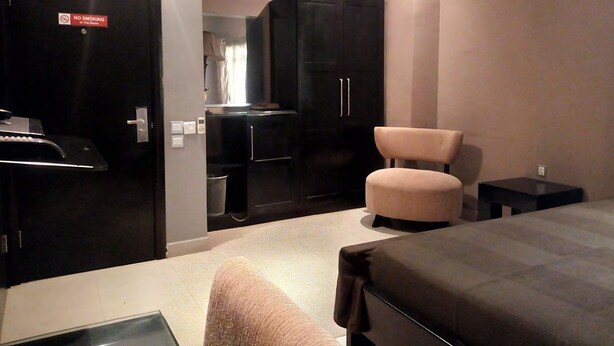 Une chambre d’hôtel avec un lit, une petite table, une chaise, une armoire et un panneau indiquant qu’il est interdit de fumer.