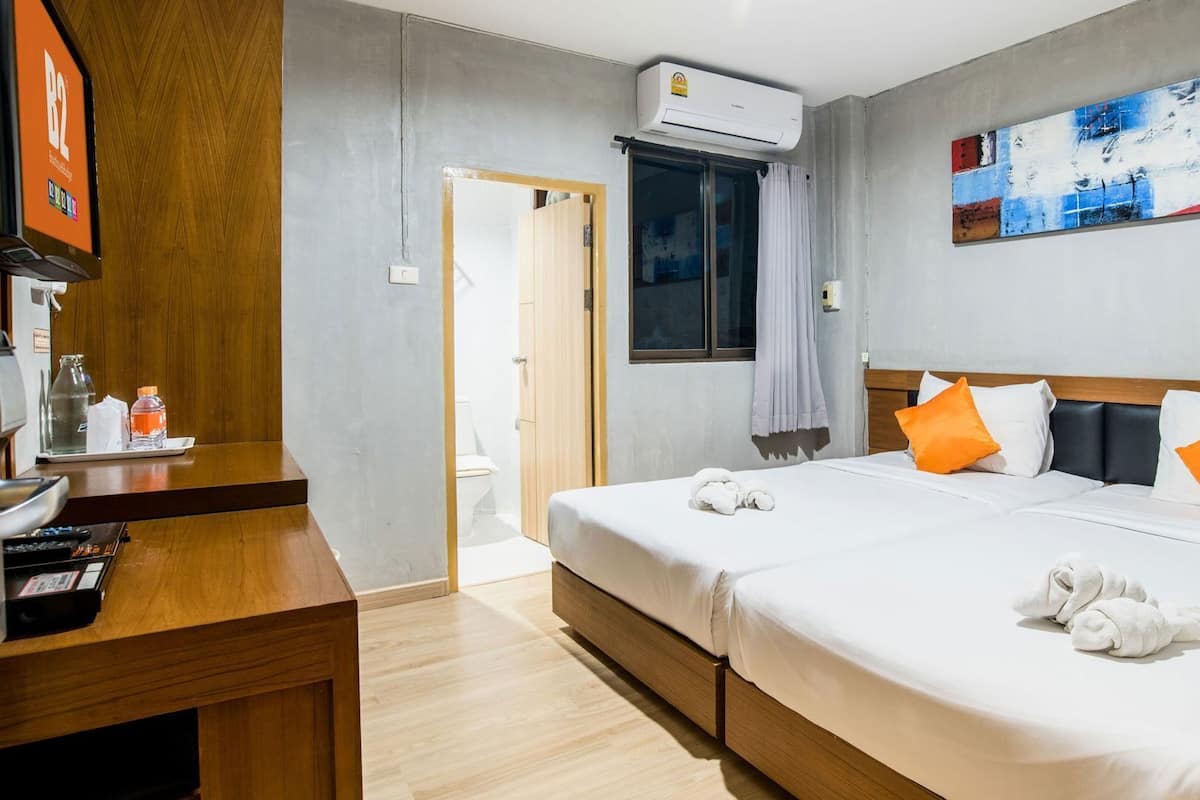 Ein Hotelzimmer mit zwei Betten, einem Schreibtisch, einem Badezimmer und einem Bild an der Wand.