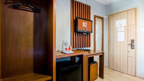 Une chambre d’hôtel avec un bureau en bois, une télévision, une petite poubelle et une porte dotée d’un panneau en bois.