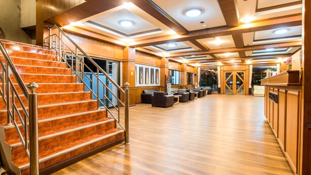 Un hall d’entrée spacieux avec un escalier en bois, un coin salon et un comptoir d’accueil.