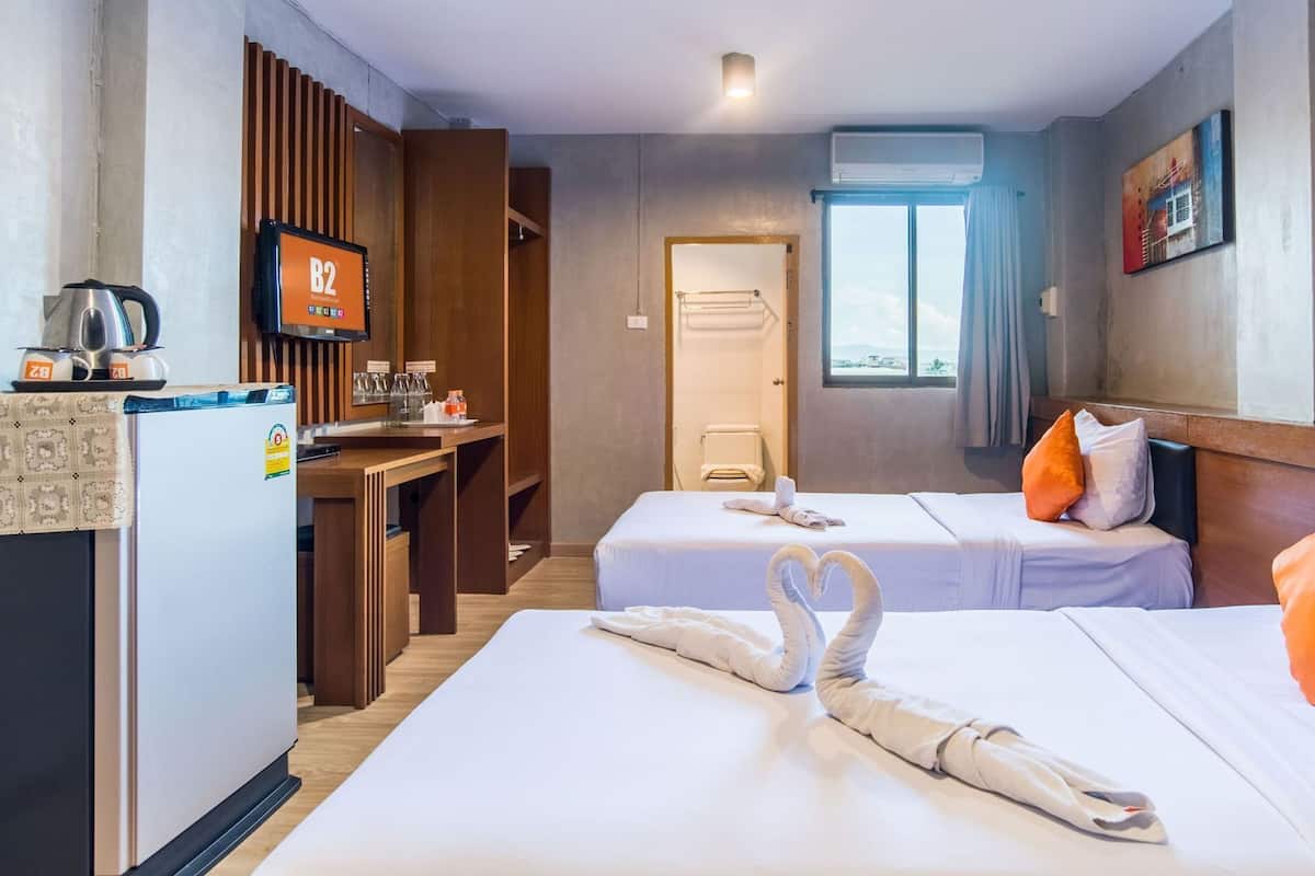 Ein Hotelzimmer mit zwei Betten, einer Küchenzeile, einem Fernseher und einem Fenster.