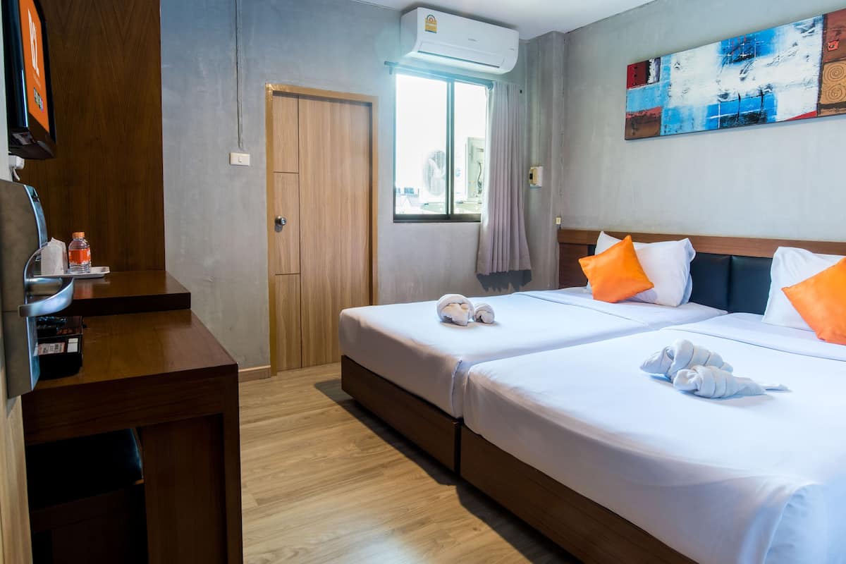 Ein Hotelzimmer mit zwei Betten, einem Schreibtisch und einem Fernseher.