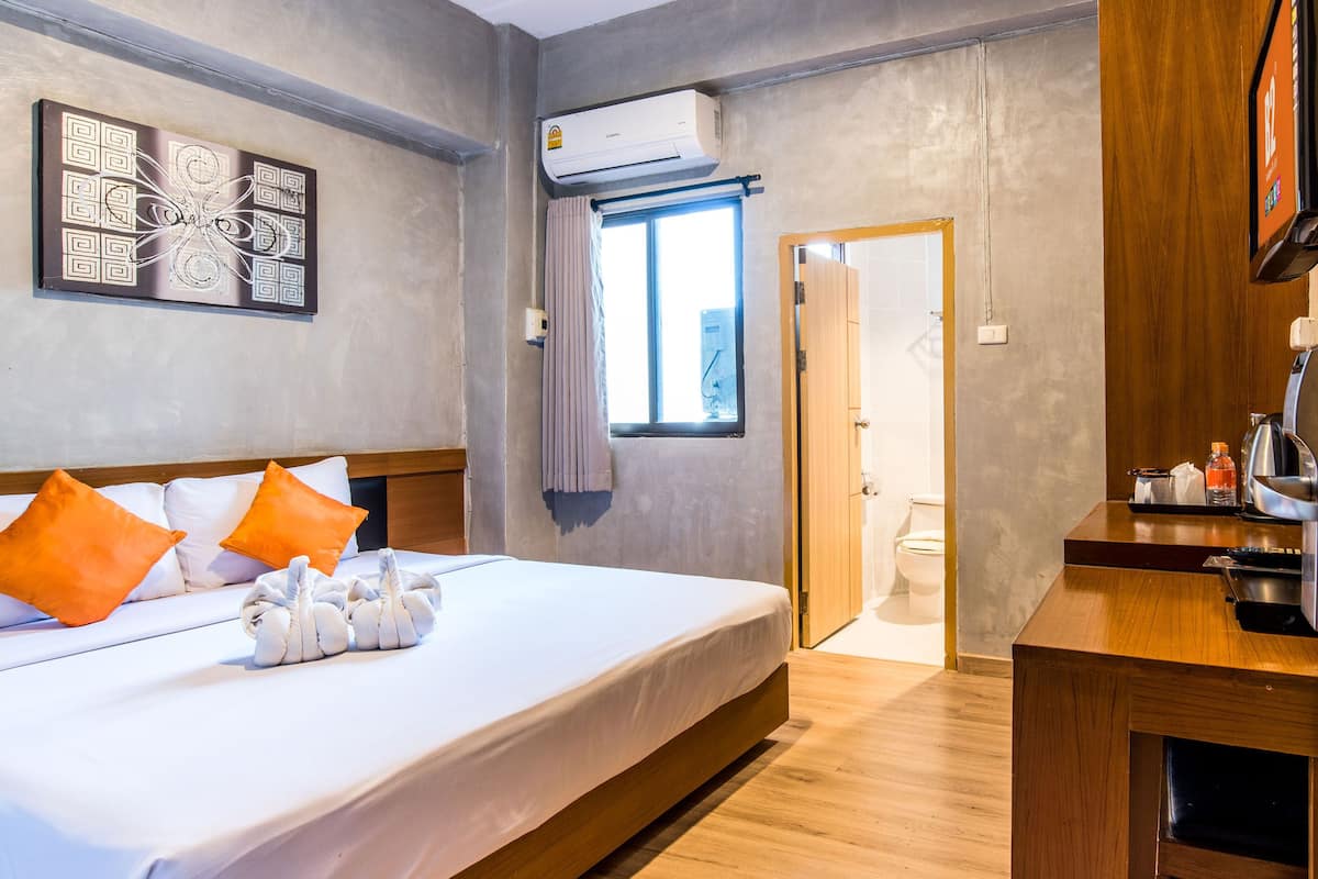 Ein Hotelzimmer mit einem Bett, einem Holztisch, einem Fernseher und einer Klimaanlage.
